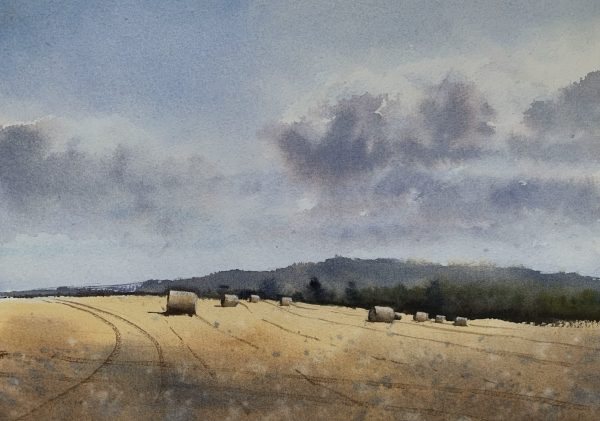 Watercolour painting of a Sussex field with hay bales and distant trees and hills in the background by artist John Haywood